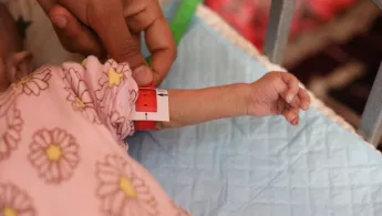 Wie viele Kinder im Gazasterifen ist dieses Baby schwer mangelernährt. Ärmchen von Kind mit Mangelernährungs-Bändchen