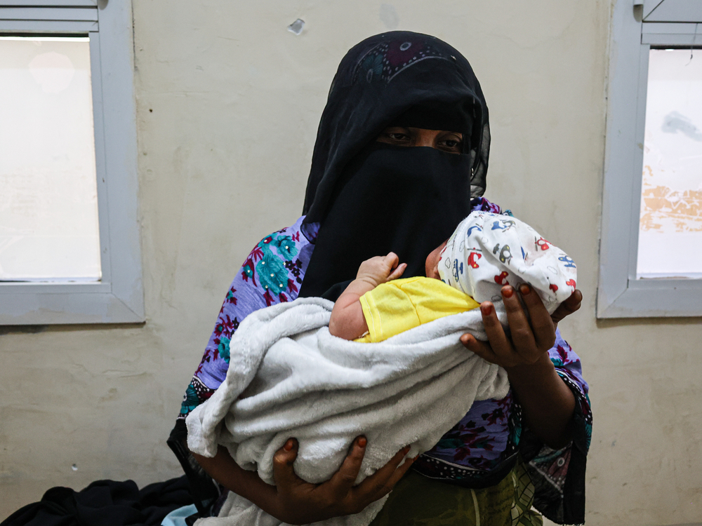 Mutter hält Baby in Arm in Entbindungsstation