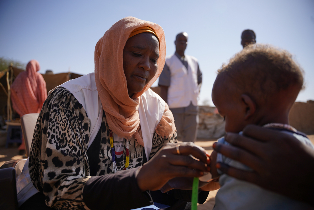 Sudan: Mitarbeiterin prüft auf Mangelernährung an Arm von Kleinkind  