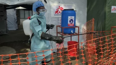 Einer unserer Mitarbeitenden in Schutzkleidung vor dem Behanldungszelt für Mpox-Patient*innen. Mitarbeiter in Schutzkleidung vor Behandlungszelt