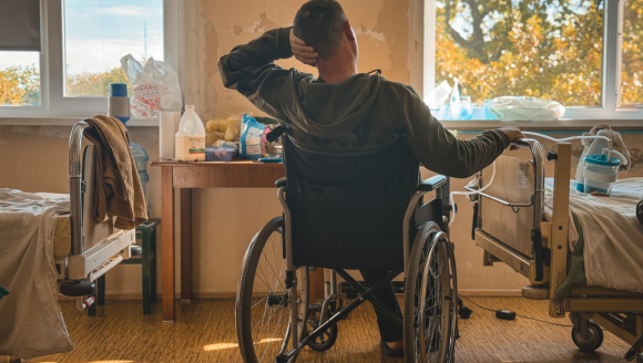 Patient sitzt im Rollstuhl in einem Krankenhauszimmer