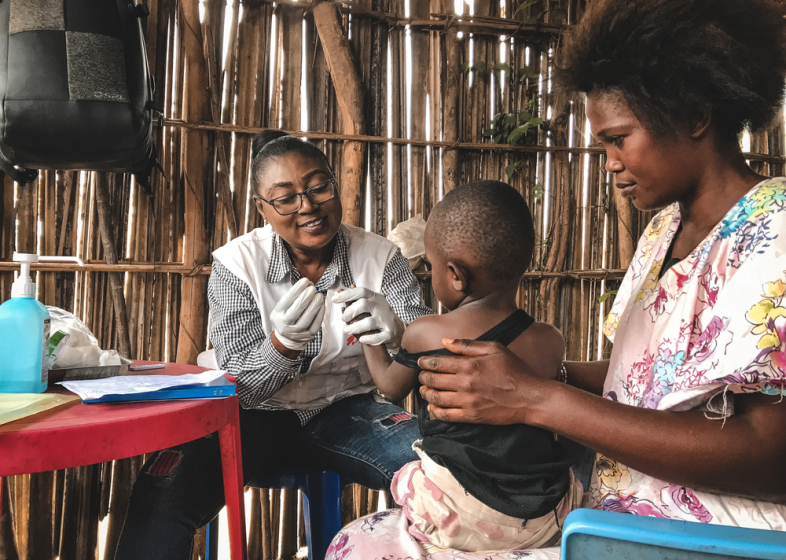 Nothilfe Afrika: Mitarbeitende untersucht Kleinkind auf Schoß der Mutter