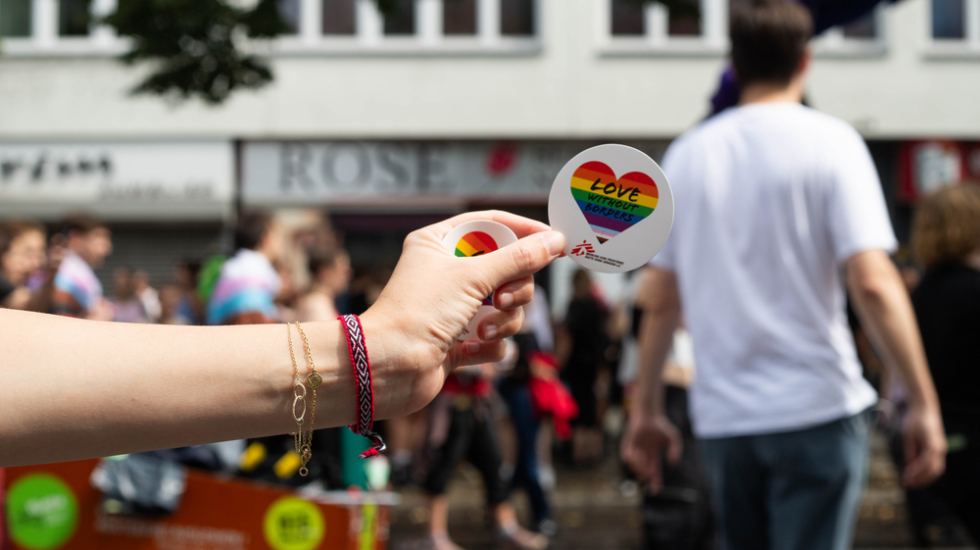 Jemand hält einen Sticker in der Hand mit der Aufschrift "Love without borders" bei der Pride-Parade in Berlin