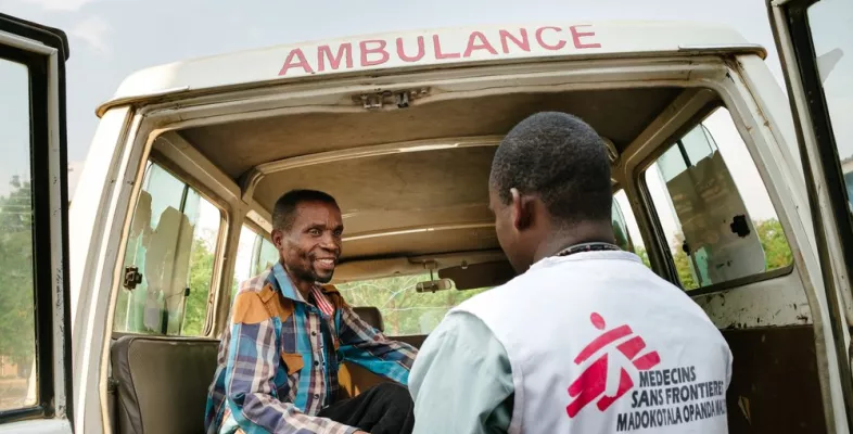 Ein Patient mit HIV wird zur weiteren Behandlung in ein Krankenhaus gebracht. Ein Mitarbeiter hilft einem Patienten an Bord eines Krankenwagens