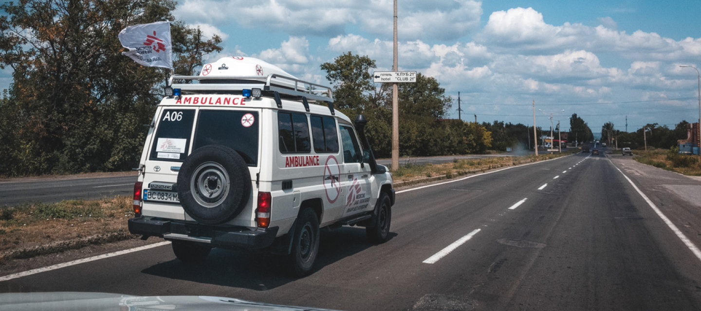 Ein weißer Krankenwagen mit dem Logo von Ärzte ohne Grenzen fährt auf einer Straße.