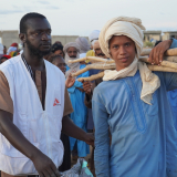 Ein junger Mann mit Material für eine Notunterkunft und ein Mitarbeiter von Ärzte ohne Grenzen in Mali.