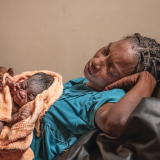 Eine erschöpfte Mutter mit ihrem Neugeborenen