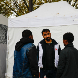 Migranten und ein Mitarbeiter vor einer mobilen Klinik in Calais