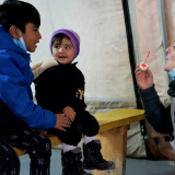 Mitarbeiterin spielt mit geflüchteten Kindern mit Seifenblasen auf Lesbos.