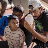 Denguefieber in Honduras: Mann und Jungen blicken in Glas mit Mücken.