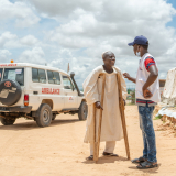 Health Promoter Abdullah redet mit einem Patienten vor der Klinik.