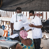 Zwei Ärzte sprechen mit einem Patienten in einem Camp für Vertriebene