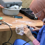 Eine Frau modelliert eine Kunststoffmaske mit einem Schleifgerät