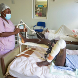 Eine Krankenpflegerin steht am Bett eines Patienten, der während des Erdbebens den Fuß gebrochen hat.