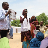 Mitarbeiter*innen der Gesundheitsförderung sprechen mit Vertriebenen in einem Camp in Borno
