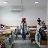 Eine Mitarbeiterin von Ärzt ohne Grenzen läuft durch den Ruhesaal nach der Geburt mit vielen Betten 